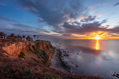 Gün batımında gökyüzünde renkli bulutlar ve sakin dalgaların kayalık kıyılara vurduğu Vicente Deniz fenerinin muhteşem uçurum manzarası, Rancho Palos Verdes, California