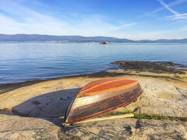 Barco de madera dio la vuelta en la roca costera — Foto de Stock