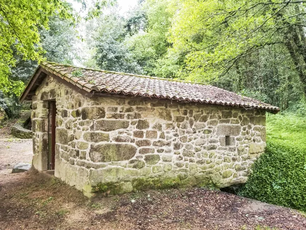 Renovated old water mill surrounded by forest trees on the stone and water route in Meis town, Galicia, Spain