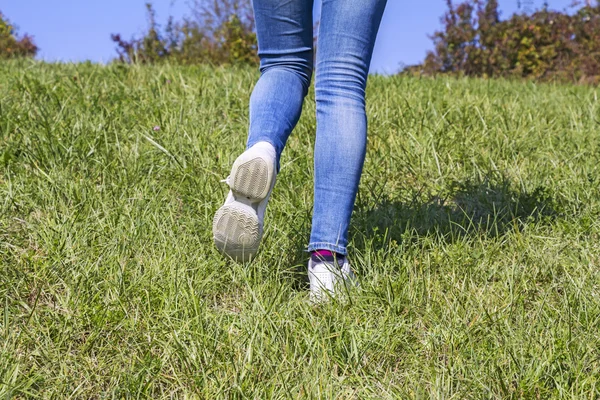 Młoda dziewczyna wędrówki w przyrodzie, na zielonej trawie — Zdjęcie stockowe