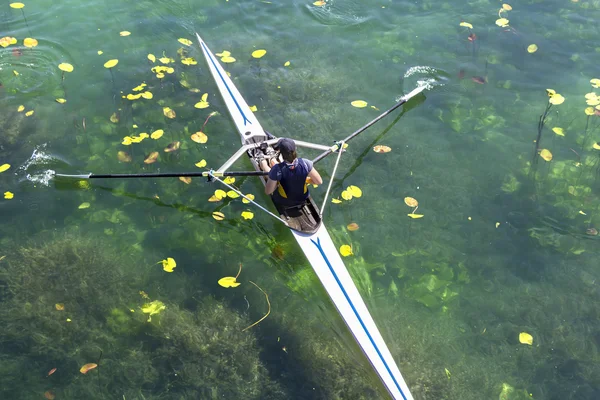 Ein junger einzelner Ruderer paddelt auf dem beschaulichen See. — Stockfoto
