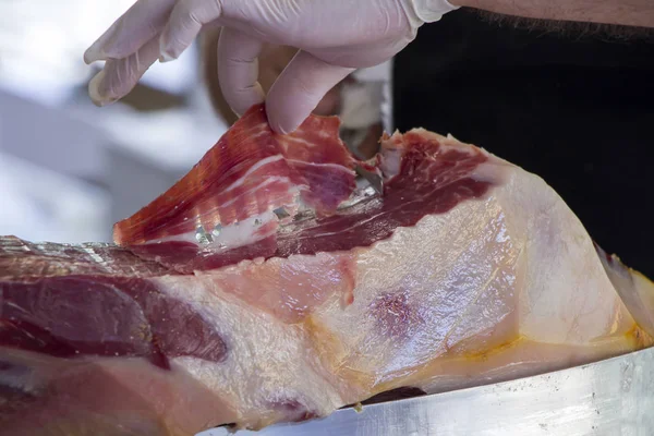 Man slicing prosciutto famous and tasty mediterranean delicatess — Stock Photo, Image