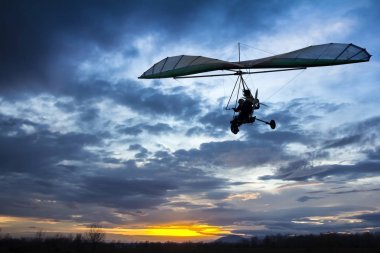 Motorlu hang glider günbatımında uçan