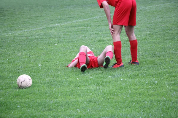 Colega de equipe com jogador ferido no jogo de futebol — Fotografia de Stock