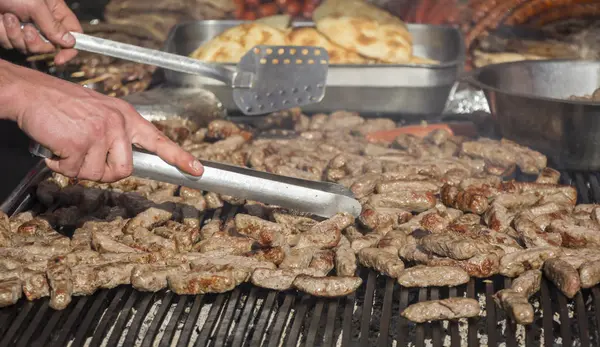 Grilling cevaps or kebabs on a grill at the street market — Stock Photo, Image