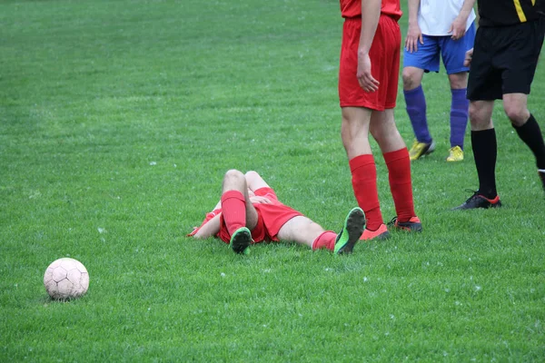 Geblesseerde speler bij de voetbalwedstrijd liggend op het gras — Stockfoto