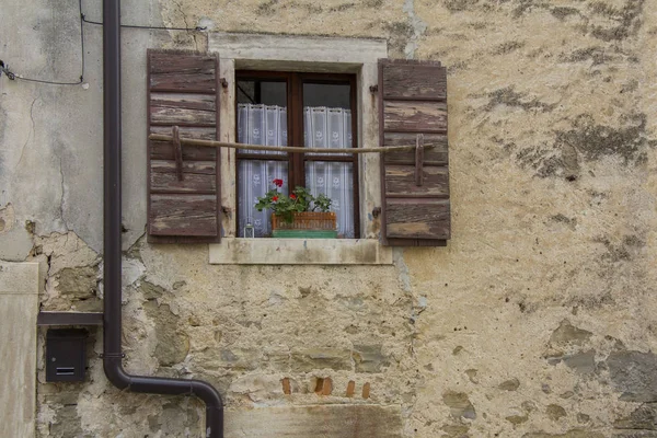 Hnědé dřevěné okenice na starý kamenný dům — Stock fotografie
