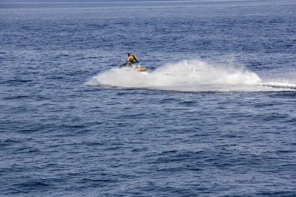 O jovem homem montando jet ski em mar azul — Fotografia de Stock