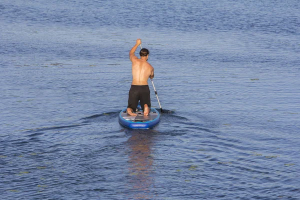 Hombre en la tabla de remo remando hacia el lago — Foto de Stock