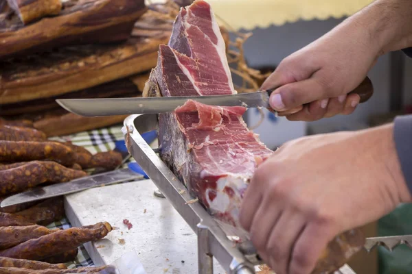 Slicing dry-cured ham prosciutto on the street market — Stock Photo, Image