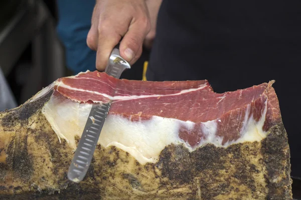 Snijden droog-cured ham hesp op de straat markt — Stockfoto