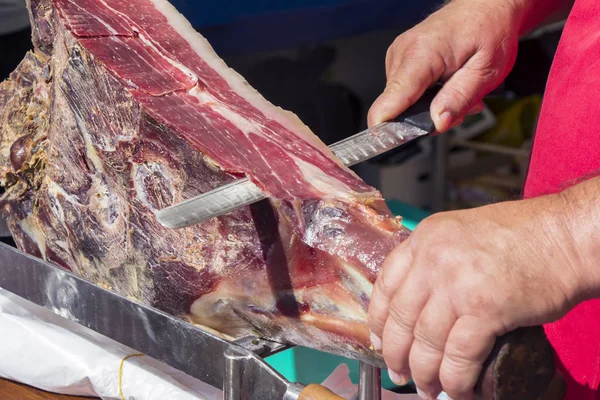 Corte de presunto curado a seco prosciutto no mercado de rua — Fotografia de Stock