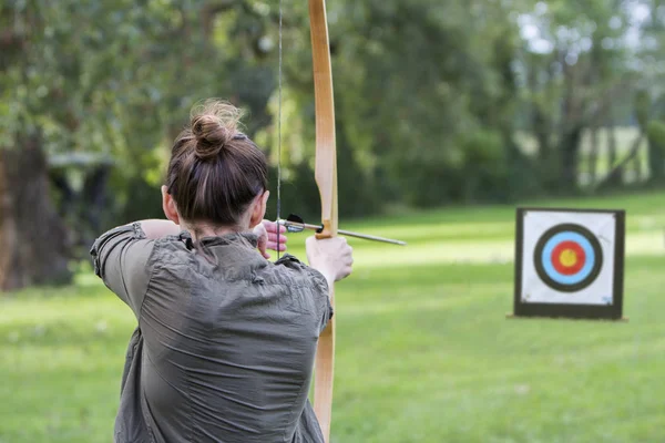 Femme archer d'utiliser un arc et flèche et tirer sur une cible — Photo