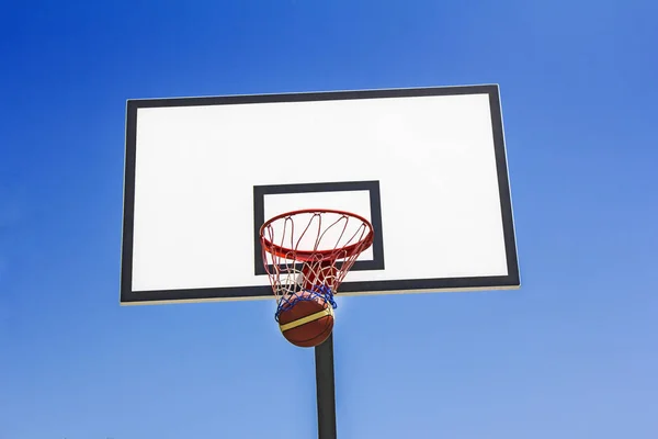 Baloncesto bola golpeó la cesta en el fondo del cielo azul —  Fotos de Stock