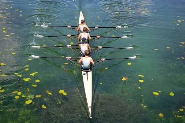 Men's quadruple rowing team on turquoise green lake — Stock Photo, Image