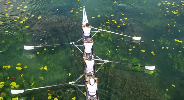 Mužský čtyřnásobný veslařský tým na tyrkysově zeleném jezeře — Stock fotografie