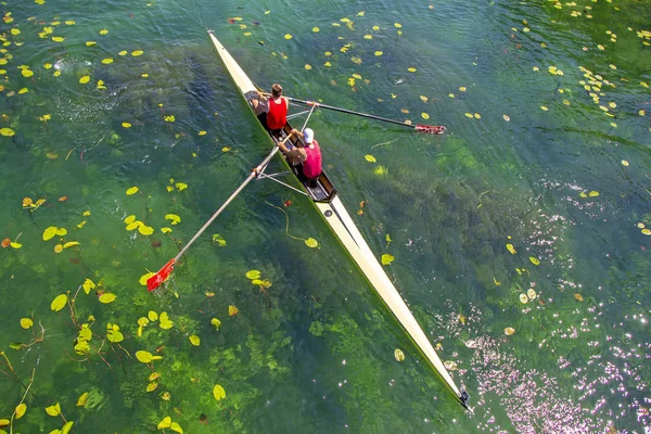 Dos jóvenes atletas remo equipo en el lago verde —  Fotos de Stock