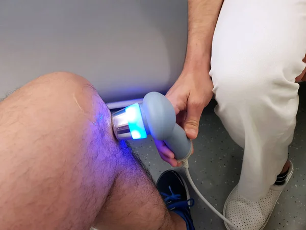 Physiotherapist is applying ultrasound therapy on the knee injury with ultrasound head transducer