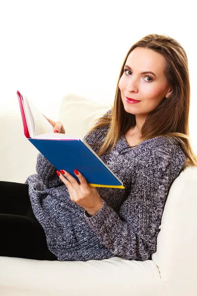 Mujer sentada en el sofá leyendo libro en casa — Foto de Stock