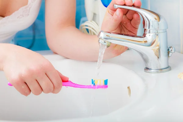 Зубная паста на зубной щетке в руке, в раковине ванной комнаты . — стоковое фото