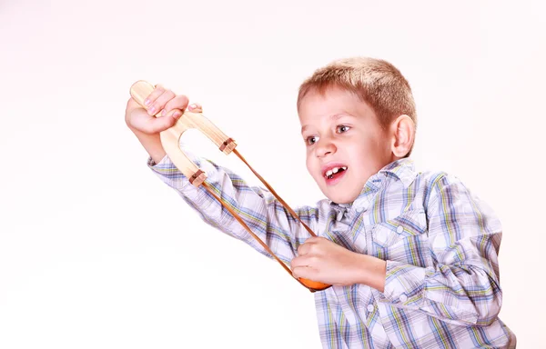 Junge schießt mit Schleuder auf Mandarine. — Stockfoto