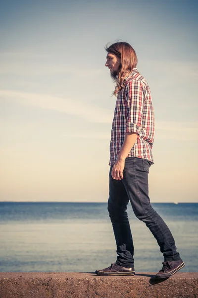 Man walking relaxed on stone wall by seaside — Stock Photo, Image