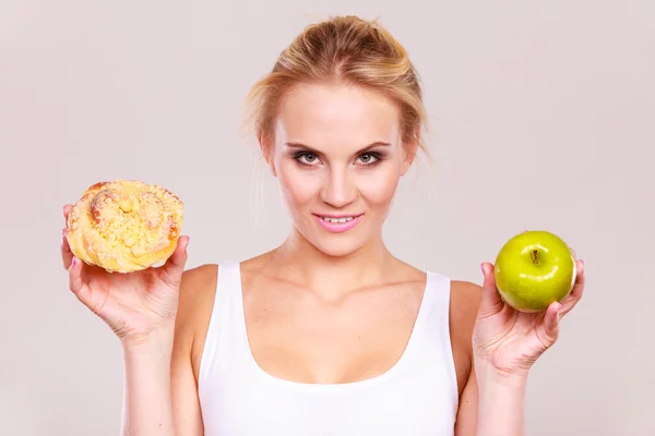 Woman holds cake and fruit in hand choosing — Stock Photo, Image