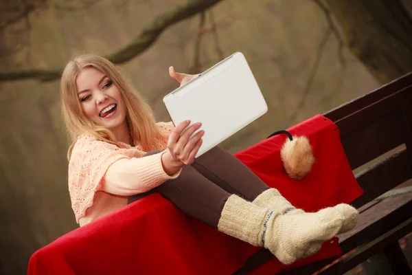 Dívka sedící na lavičce s tabletem. — Stock fotografie