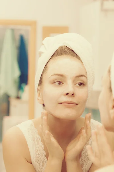 Mujer aplicando crema mascarilla en la cara en el baño —  Fotos de Stock