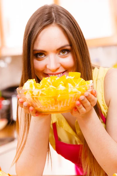 Woman holds bowl full of sliced orange fruits — Stock Photo, Image