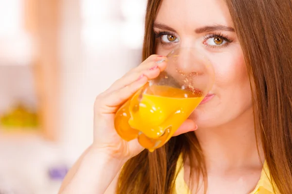 Γυναίκα στην κουζίνα πόσιμο φρέσκο χυμό πορτοκάλι — Φωτογραφία Αρχείου