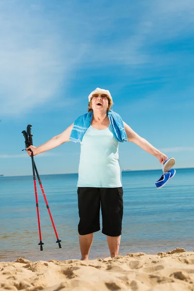 Mujer mayor practicando nordic walking en la playa —  Fotos de Stock
