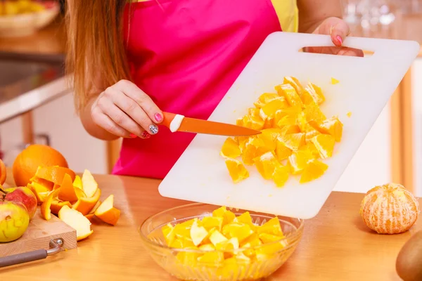 Mulher dona de casa na cozinha cortando frutas laranja — Fotografia de Stock