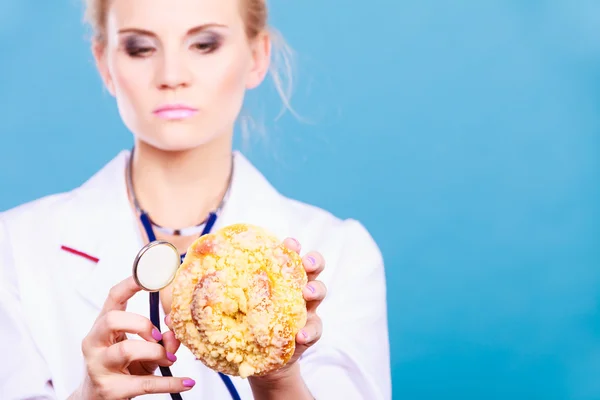 Dietista examinar bollo de rollo dulce con estetoscopio — Foto de Stock