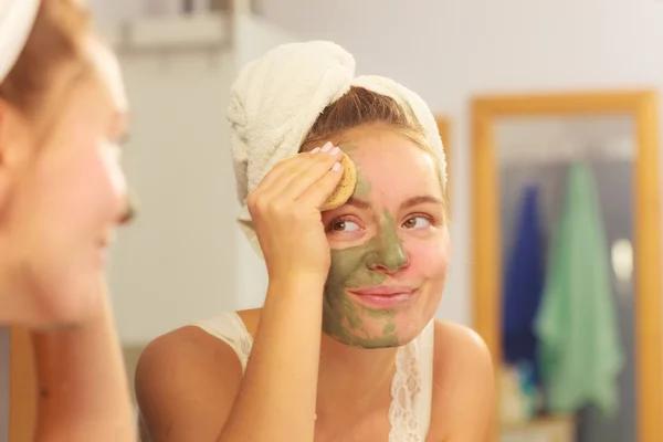 Mulher removendo máscara de barro facial lama no banheiro — Fotografia de Stock