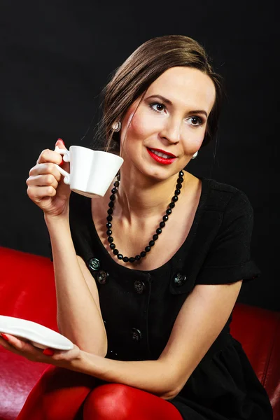 Retro vrouw houdt theekopje zittend op bank — Stockfoto