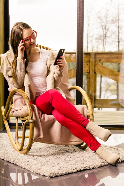 Vrouw zit op stoel met behulp van telefoon thuis — Stockfoto