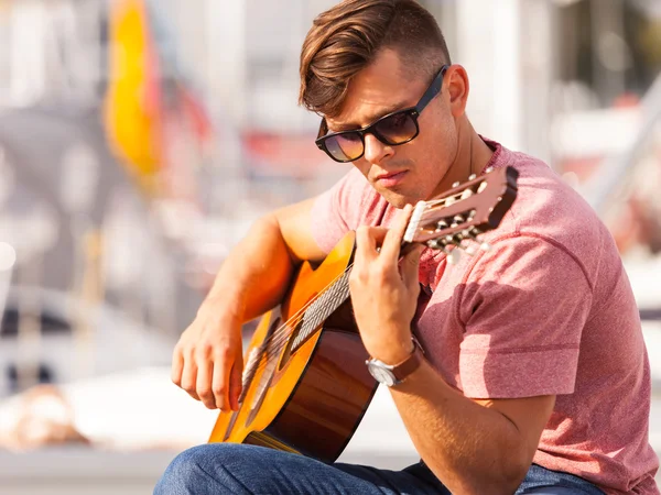 Junger Gitarrist sitzt auf Seebrücke. — Stockfoto