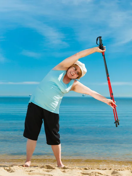 Senior woman warming up with walking poles — Stock Photo, Image