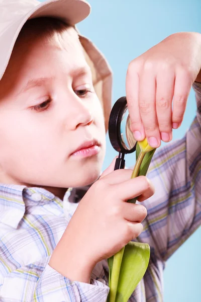 Giovane ragazzo tenere fiore e lente d'ingrandimento . — Foto Stock