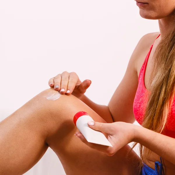 Mujer poniendo ungüento en lesión cuidado de la piel de rodilla — Foto de Stock
