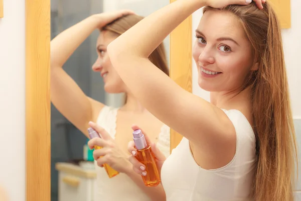 Vrouw het verzorgen van haar lange haren cosmetische olie aanbrengen — Stockfoto