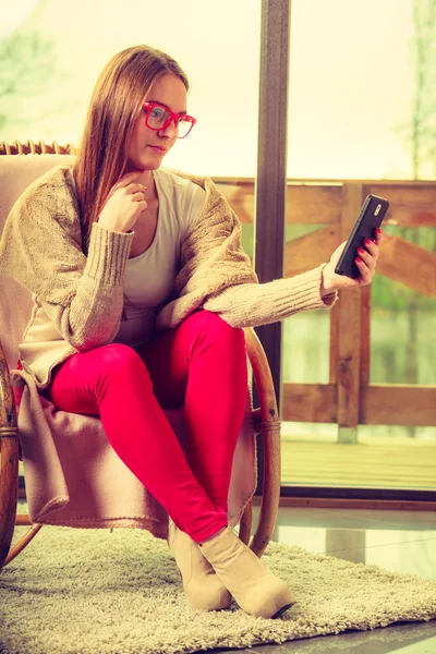 Nainen istuu tuolilla puhelimitse kotona — kuvapankkivalokuva