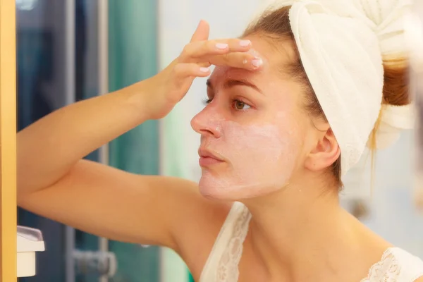 Mujer aplicando crema mascarilla en la cara en el baño — Foto de Stock