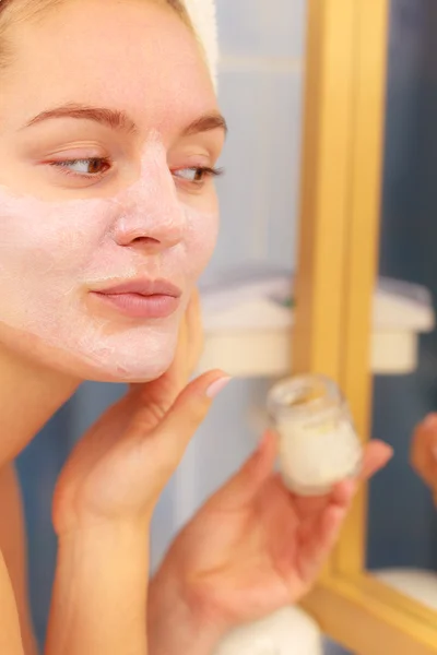 Mujer aplicando crema mascarilla en la cara en el baño —  Fotos de Stock