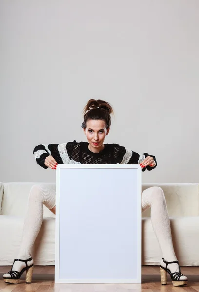 Mulher no sofá segurando placa de apresentação em branco. — Fotografia de Stock