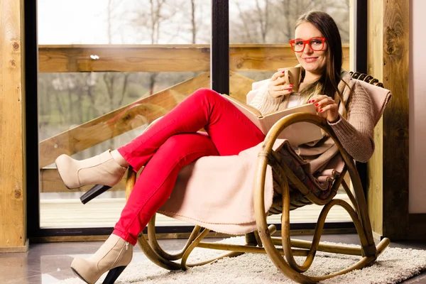 Mujer sentada en silla leyendo libro en casa — Foto de Stock