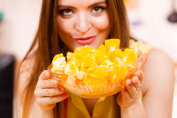 Woman holds bowl full of sliced orange fruits — Stock Photo, Image