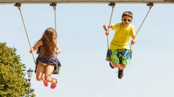 Dwoje dzieci zabawy na swingset. — Zdjęcie stockowe