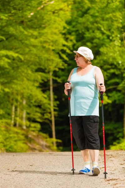 Starší žena cvičí nordic walking v parku — Stock fotografie